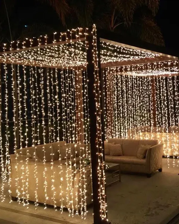 Fairy lights are my secret weapon for creating a magical ambiance. Here, I've draped the entire pergola in curtains of warm fairy lights, turning the seating area into a cozy, starlit grotto.