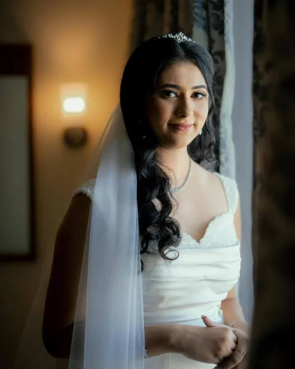 A beautiful portrait of my Christian bride by the window. Her soft glam makeup and simple white gown create a look of pure, understated elegance.