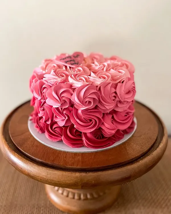 A beautiful cake featuring pink ombre buttercream rosettes. This design is perfect for birthdays and anniversaries, with a little heart plaque that reads "Happy 50th young lady!"