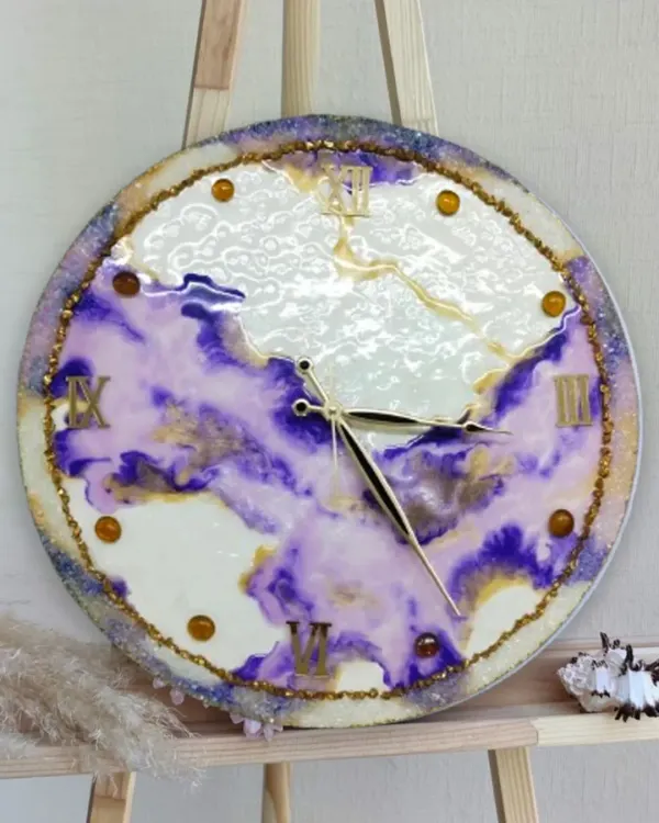 A closeup of a stunning resin art clock, showcasing the beautiful swirls of purple and gold. Our students learn to master these fluid techniques to create functional art.