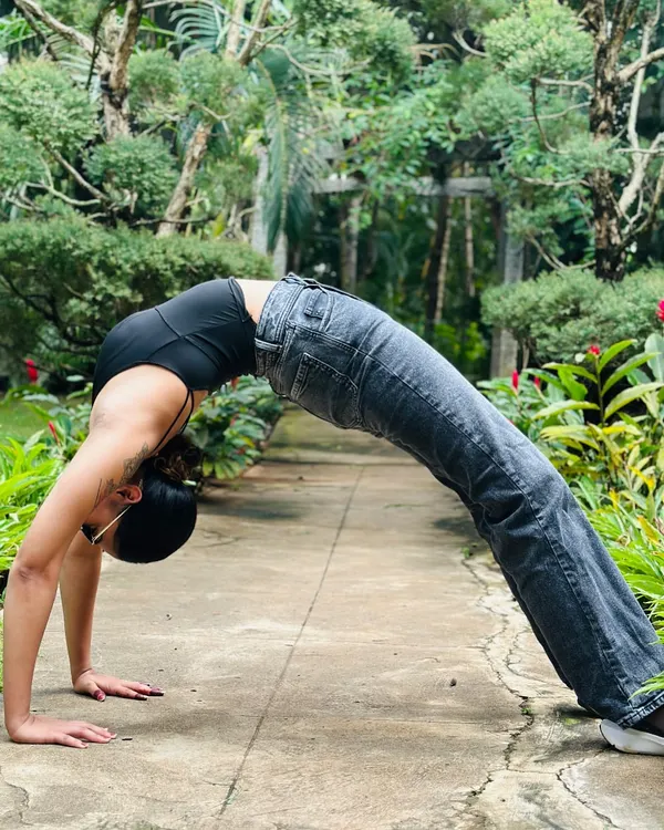 A deep Urdhva Dhanurasana (Wheel Pose) in a garden. This powerful backbend opens the entire front of the body and builds strength in the arms, legs, and spine.