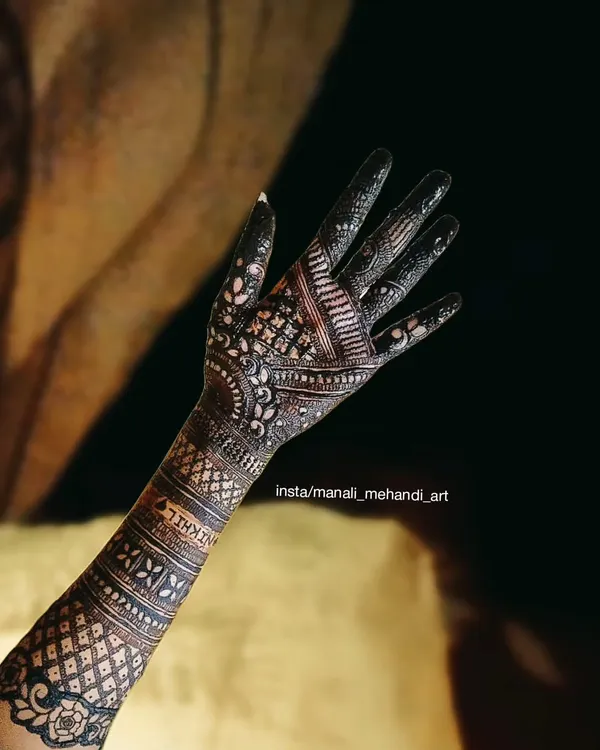 A beautiful example of a full-hand traditional mehandi design. The pattern uses fine lines, dots, and geometric shapes to create a dense and intricate look, with the name 'Nikhil' subtly included.