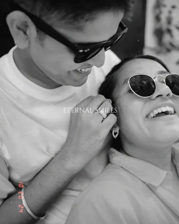 A playful and candid black and white moment. The sunglasses add a cool vibe, but their genuine smiles and laughter are what make this pre-wedding portrait truly special.