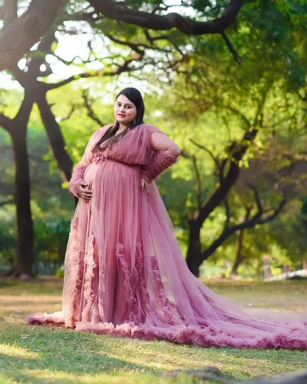 A princess moment in the park. This beautiful pink tulle gown looks absolutely dreamy against the soft green backdrop, creating a fairytale maternity portrait.
