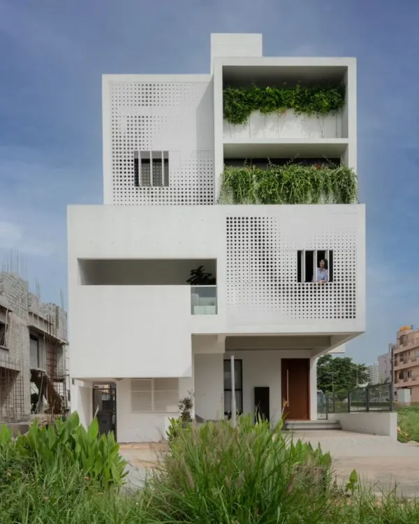 The LUCID House, a contemporary residential building designed for an urban setting. The facade features stacked, box-like volumes with integrated planters and a distinctive perforated screen, showcasing a modern architectural language.