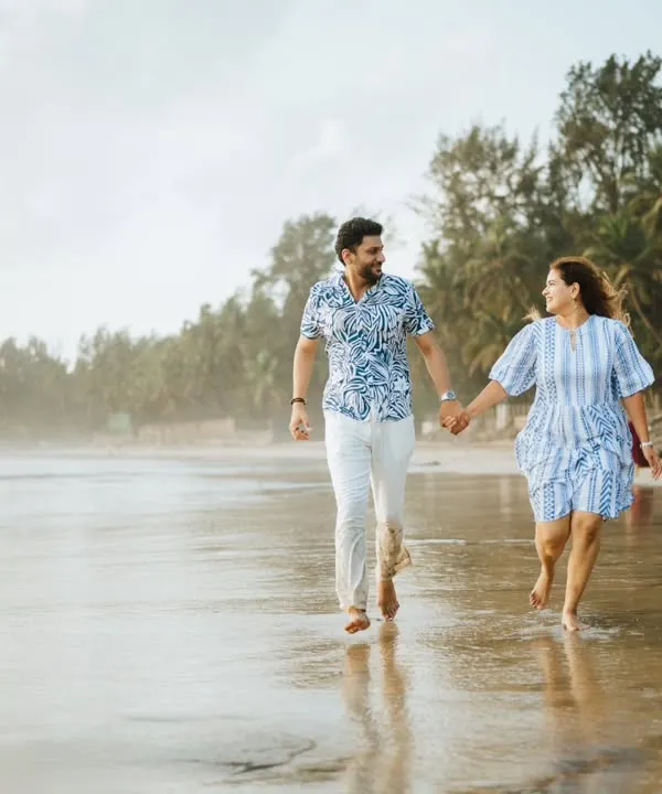 A happy, candid shot of a couple running along the shoreline. This image is full of energy and joy, capturing a perfect moment of fun during their beach pre-wedding shoot.