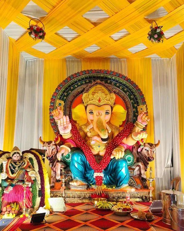 An outdoor pandal decoration for Ganesh Chaturthi. This setup features a yellow and white draped structure to house the large Ganesha idol, creating a grand space for the festival.