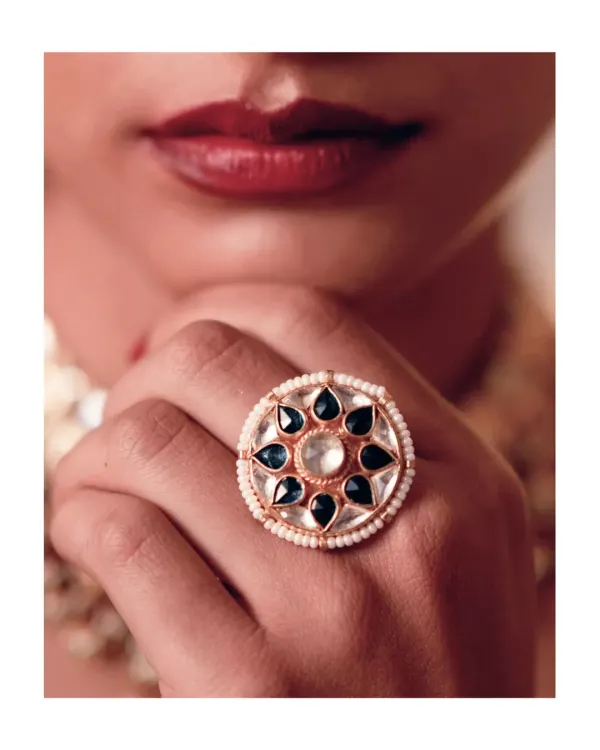 A statement without saying a word. This oversized cocktail ring, featuring gold, pearl, and green stones, is a striking piece that adds a touch of festive glamour to any evening look. It’s the kind of detail that completes an outfit.