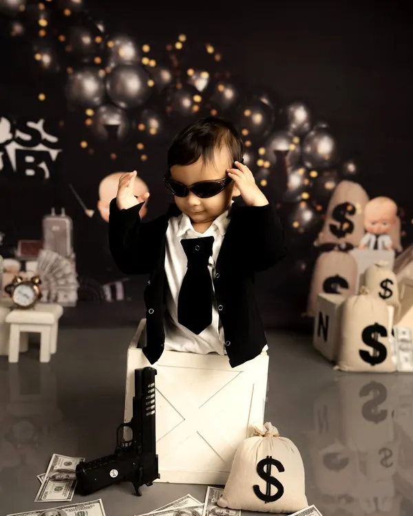 Ready for business, this little one is rocking the 'Boss Baby' look. I use props like toy guns and money bags to create a playful and cinematic scene for a memorable first birthday photoshoot.