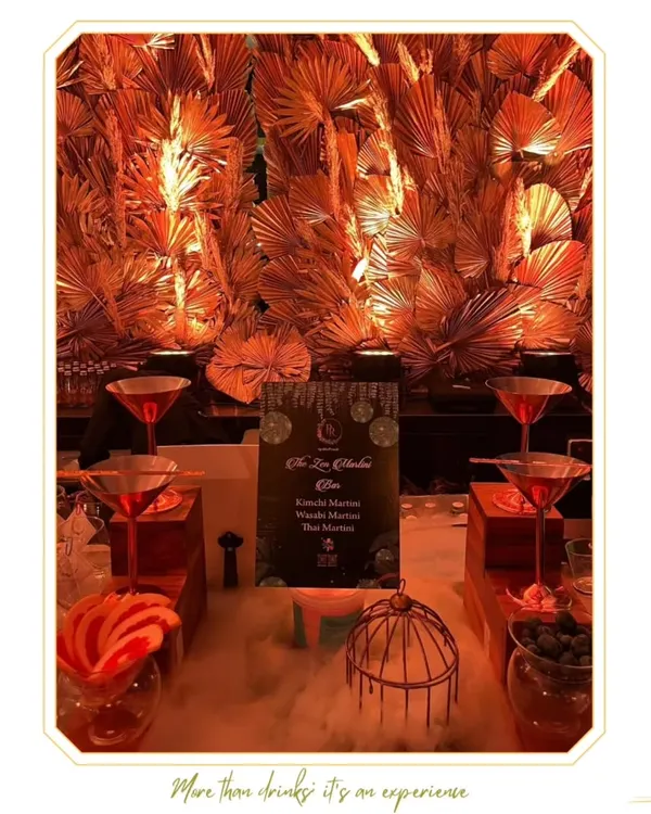 A dramatic Martini Bar setup featuring dry ice for a smoky, theatrical effect. The golden palm backdrop and tiered display create a sense of opulence and sophistication.