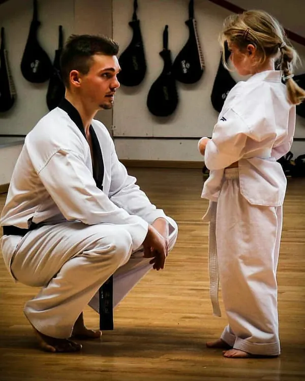 An instructor takes a moment to speak with a young student. This is where the real teaching happens. It's about mentorship, building trust, and passing on the values of respect and perseverance one-on-one.