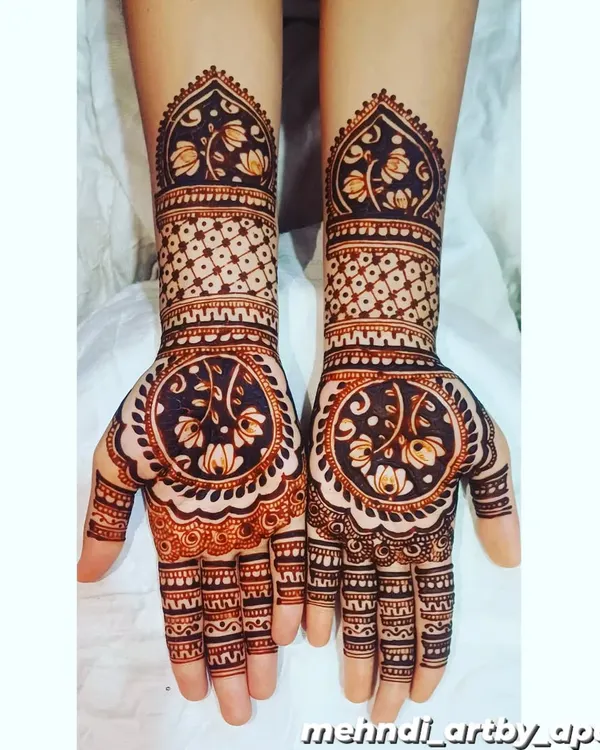 This design features a beautiful reverse-fill technique, where the background is shaded dark to make the lotus and vine patterns on the palm pop. The forearm has a lighter, geometric pattern for contrast.