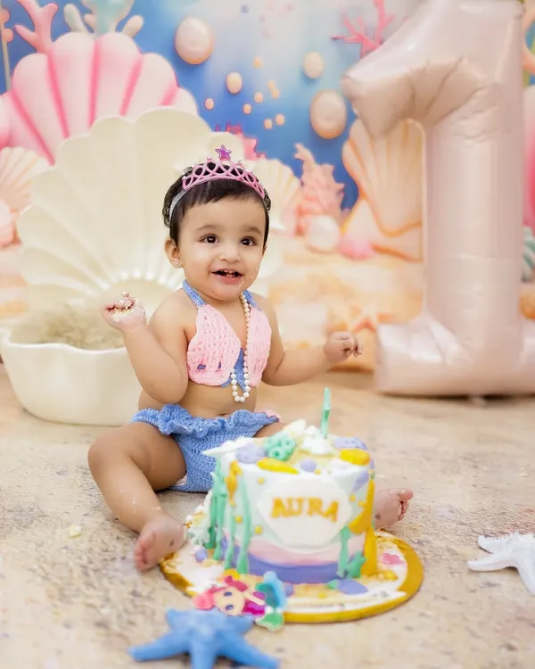 A magical mermaid-themed first birthday! This little princess is all smiles with her beautiful cake and under-the-sea backdrop.
