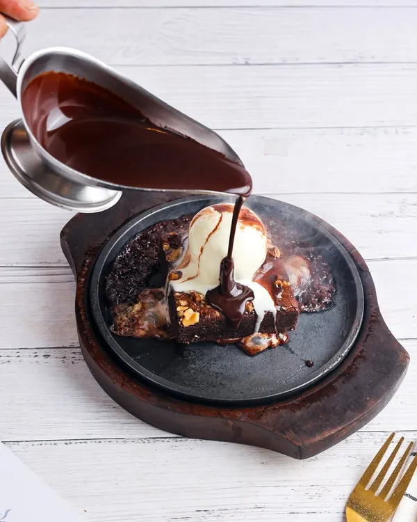 I love capturing the drama of a dish, like the steam rising from this sizzling brownie as rich chocolate sauce is poured over vanilla ice cream. This is the kind of action shot that makes customers stop and crave.