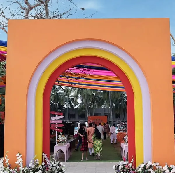 The grand entrance to the 'Spectrum of Love' Haldi, featuring a colorful rainbow archway that invites guests into a world of joy.