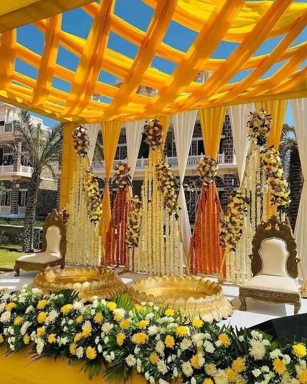 This stunning couple's Haldi setup is a perfect example of how we blend tradition with grandeur. We used a vibrant yellow color scheme with intricate floral arrangements to create a picture-perfect ceremony space for this outdoor wedding event.