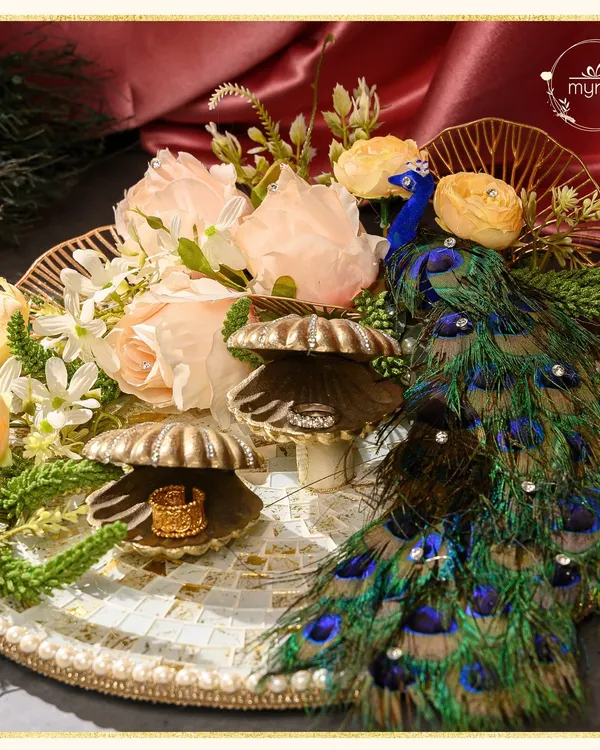 For an engagement ceremony, the ring platter should be as breathtaking as the moment itself. I designed this regal platter with a peacock motif, delicate florals, and shell ring holders to create a perfect start to a forever journey.