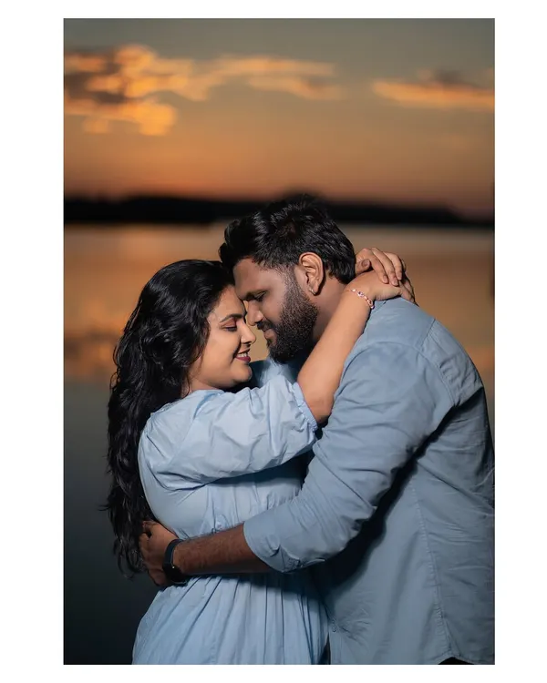 An intimate embrace as the sun sets over the water. The warm glow of the golden hour creates a soft, romantic atmosphere perfect for couple portraits.