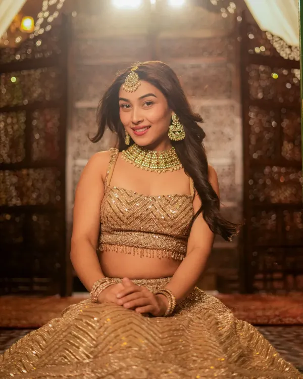 A stunning bridal or festive look, captured with soft lighting to highlight the intricate gold lehenga and jewelry. This is perfect for a designer's catalog or a bridal portfolio.