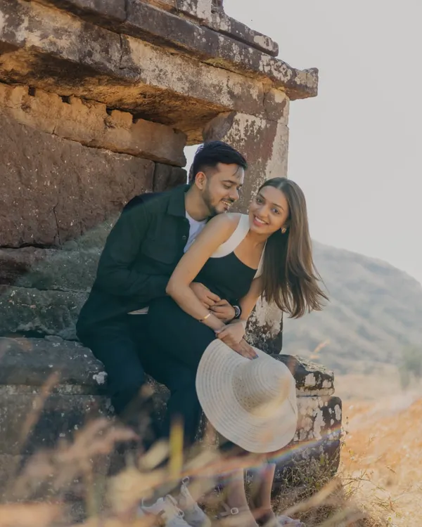 A sweet, candid moment captured against ancient stone ruins and a vast, hilly landscape. The couple's gentle embrace and happy smiles tell a story of love that feels both timeless and natural.