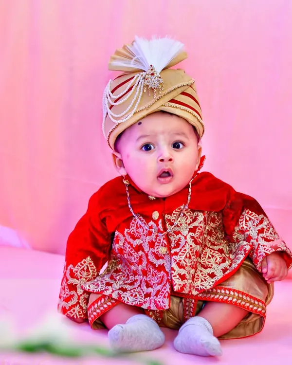 Capturing the adorable innocence of a baby boy during his naming ceremony, dressed in a traditional sherwani. My kids' photography focuses on their natural expressions.