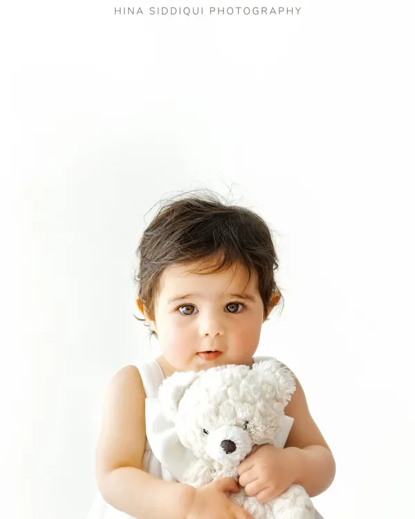 A quiet moment with a favorite friend. This close up portrait highlights those big, curious eyes and the sweet comfort a baby finds in their teddy bear, creating a truly heartwarming image.