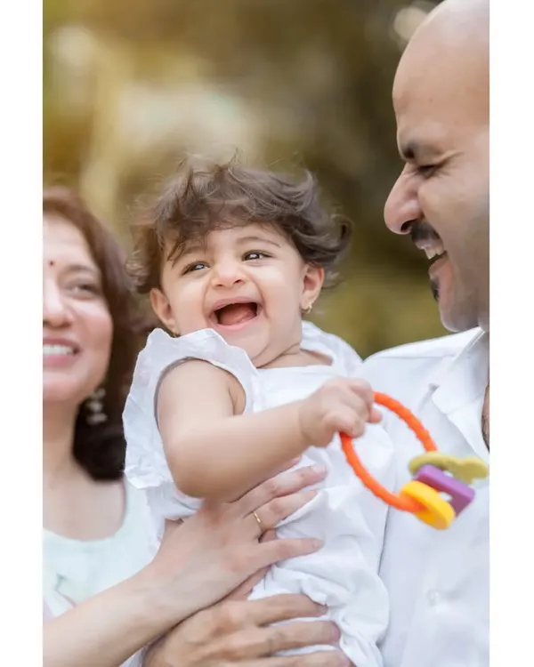 A perfect family portrait filled with laughter. Baby Anwita shares a joyful moment with her parents during her first birthday shoot. Including family in the photos creates memories for everyone.