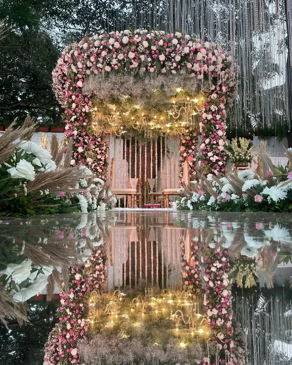 A breathtaking mandap where pastel florals meet the dramatic reflection of a mirror aisle. The design is enhanced with pampas grass and warm lighting for a romantic, bohemian feel.