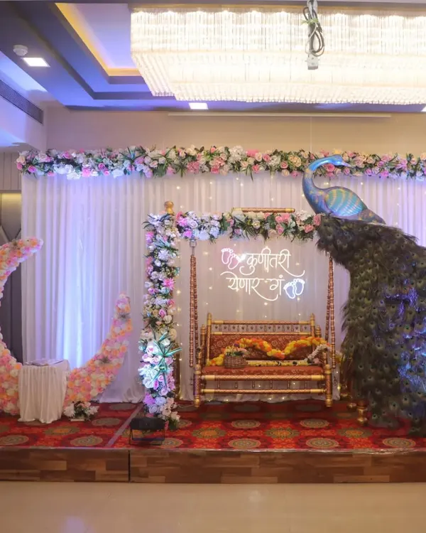 This is one of my favorite Dohale Jevan setups. It combines all the popular elements: a traditional jhula, a beautiful peacock prop, a custom neon sign, and a floral moon seat for photos.