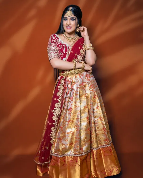 This is a classic Langa Voni from my collection, featuring a red and gold brocade skirt and a beautifully embroidered maroon blouse. It’s a perfect outfit for an engagement ceremony.