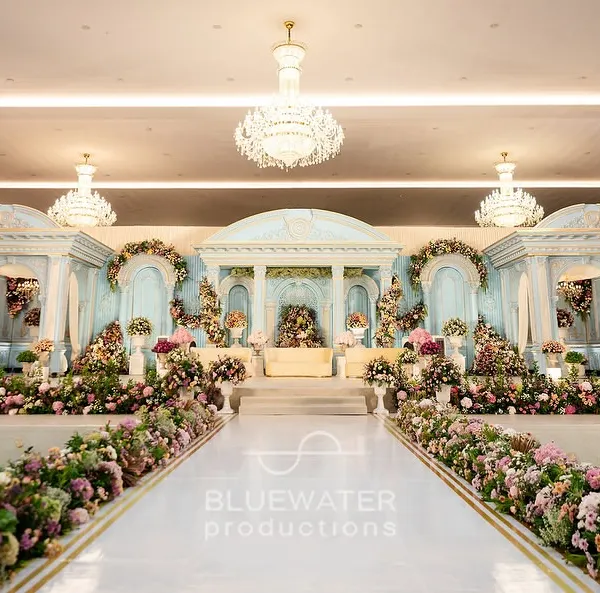 We transformed an indoor hall into a modern-day palace, with a grand stage featuring powder blue Romanesque architecture and lush, cascading florals. This is how we bring ambitious visions to life.