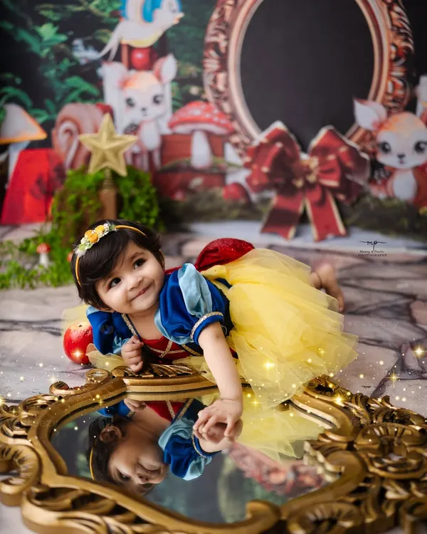 Our little Snow White finds her reflection in the magic mirror. This enchanting woodland setup, complete with forest creatures, brings the classic fairytale to life.