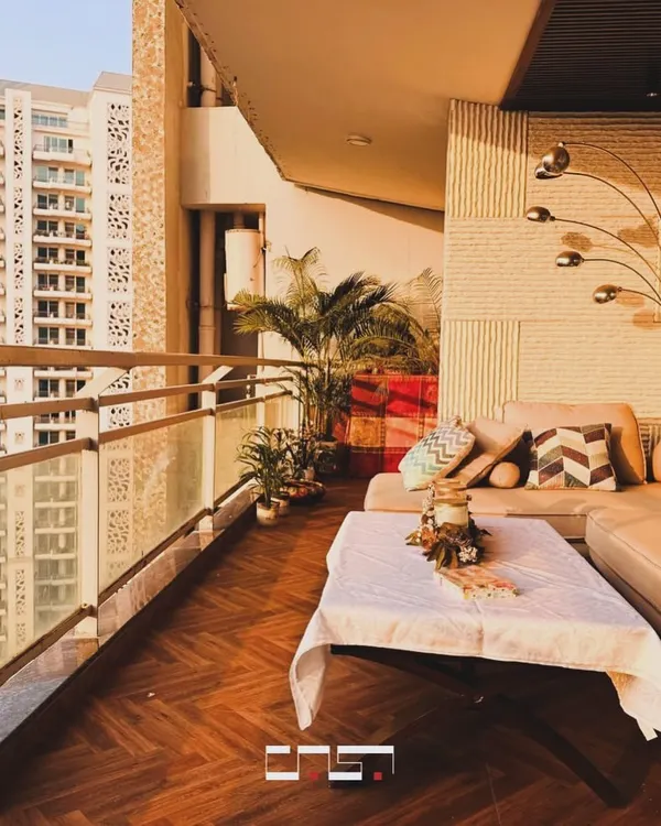 This spacious balcony is designed as a luxurious outdoor lounge, with a large L-shaped sofa, herringbone wood flooring, and a modern floor lamp, perfect for enjoying the sunset.