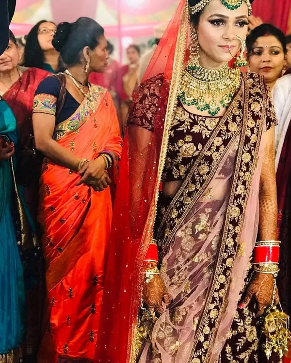 A bride captured during her wedding ceremony in a stunning maroon velvet lehenga. The heavy gold embroidery and matching jewellery create a timeless and regal bridal look.
