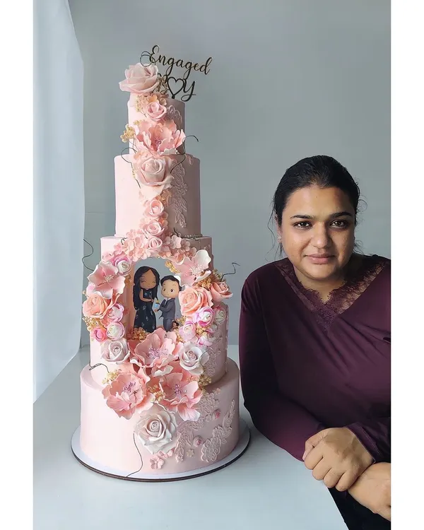 Your proposal story, immortalized in cake. This grand five-tier engagement cake features a custom, hand-sculpted scene of the couple's proposal, surrounded by hundreds of handcrafted sugar flowers.