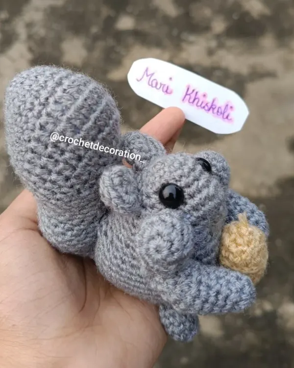This is our 'Mari Khiskoli', a signature crochet squirrel that has become a customer favorite. Each one is handmade with soft grey yarn, featuring a bushy tail and a tiny acorn, making it a perfect, durable companion for imaginative play.