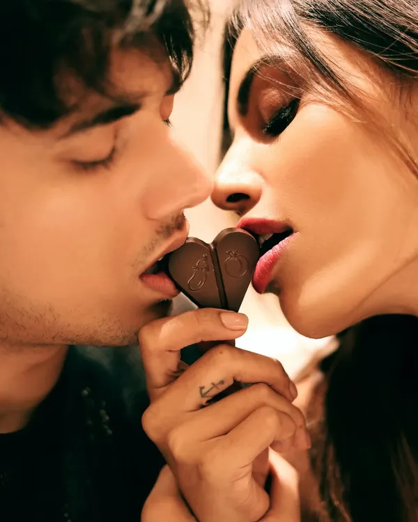 This is storytelling in a single frame. A close, intimate moment shared over a piece of heart-shaped chocolate, creating a powerful emotional connection for the brand.