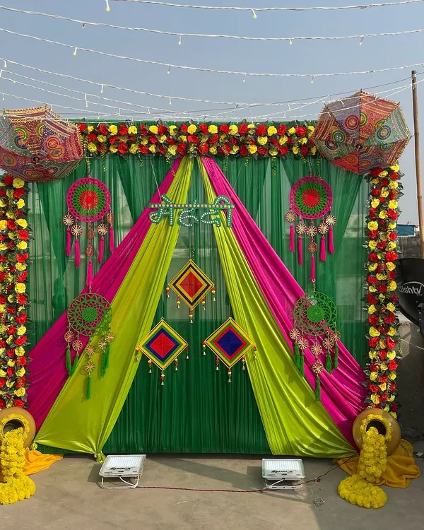 A vibrant outdoor Mehendi backdrop. I used a combination of green, yellow, and pink drapes, Rajasthani umbrellas, dreamcatchers, and marigold floral arrangements for a festive and colorful look.