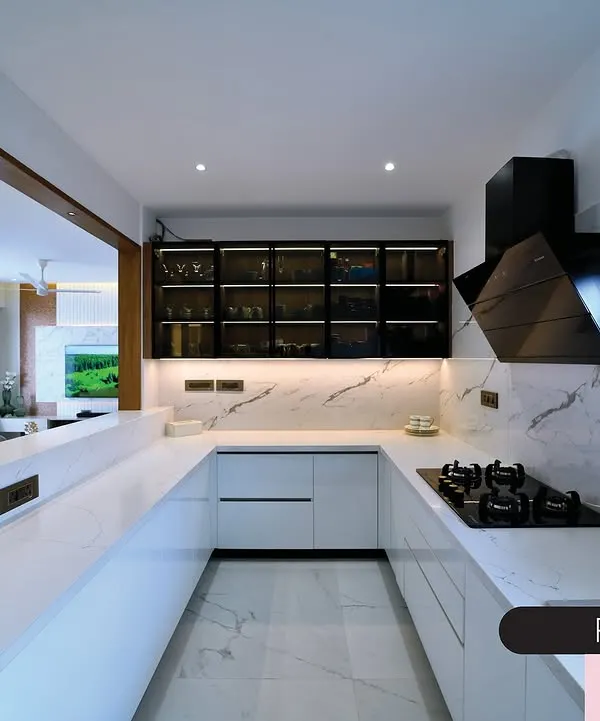 This pristine white kitchen is a study in modern minimalism. The U-shaped layout, handleless cabinets, and marble-clad countertops create a sleek and highly functional cooking space.