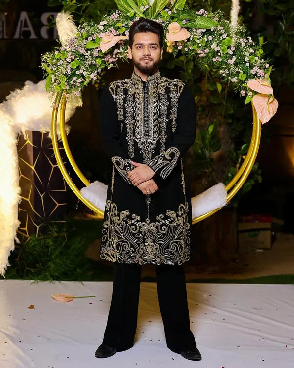 A happy client dressed for a golden night. He is wearing our classic black velvet kurta with intricate gold handwork, a perfect choice for a glamorous Diwali party or wedding reception.