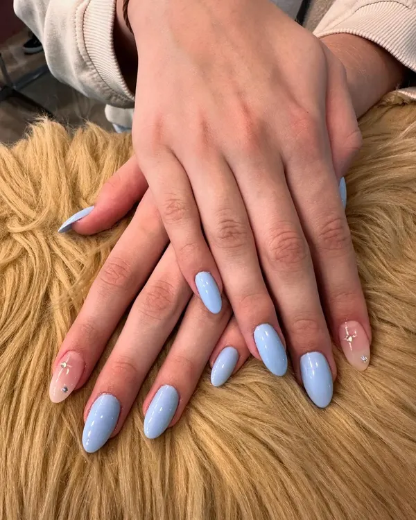 A beautiful example of simple elegance. This manicure features a solid, glossy baby blue polish on perfectly shaped oval nails, with a subtle glitter accent nail for a touch of sparkle.