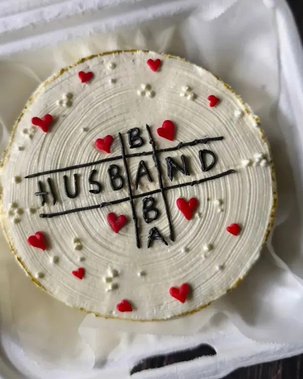 A clever design for a joint birthday celebration. This cake features a tic-tac-toe game with "HUSBAND," "DAD," and "BABA" to honor a father and grandmother.