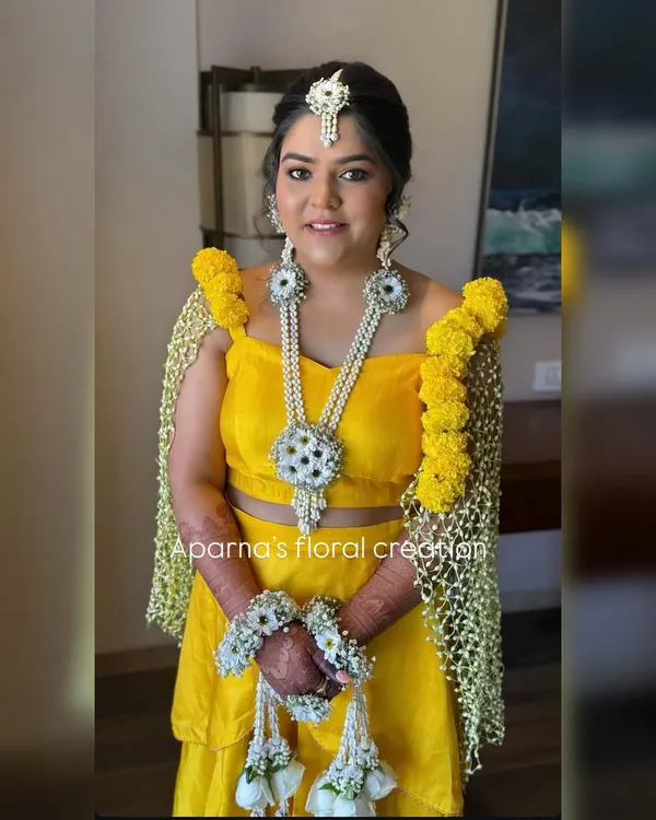 For this bride's Haldi ceremony, I created a full set of fresh flower jewellery and a matching floral dupatta, also known as a 'shela'. The bright yellow marigolds and contrasting white flowers create a look that is both traditional and vibrant.
