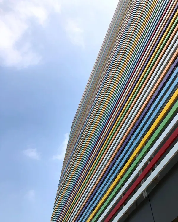 The facade of a rehabilitation center in Bangalore, featuring a vibrant, multi-colored louvered screen. This design element provides sun protection while creating a cheerful and dynamic exterior.