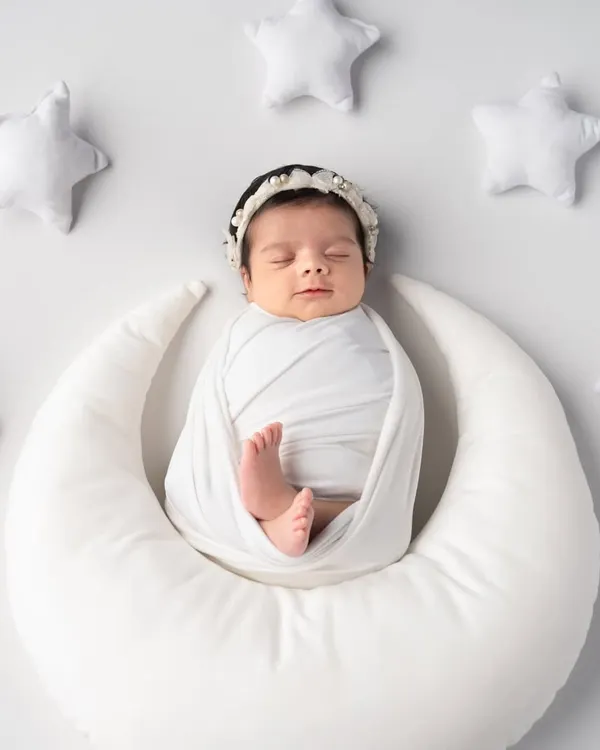 Like a tiny angel sleeping on the moon, surrounded by soft, white stars. This classic white-on-white setup is perfect for creating a pure and timeless newborn portrait.
