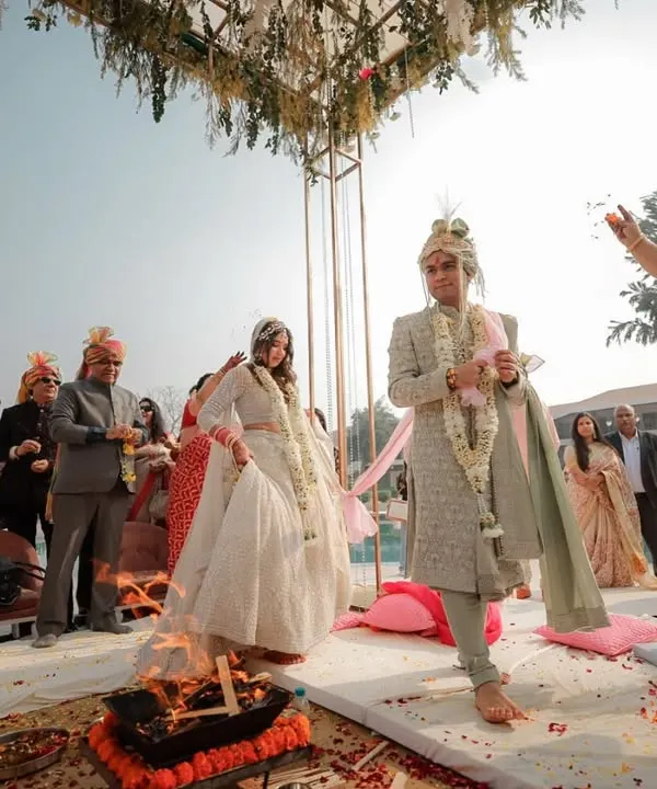 A wide angle shot of the Pheras, showing the couple circling the sacred fire as their families look on. This image captures the solemnity and community aspect of a Hindu wedding ceremony.