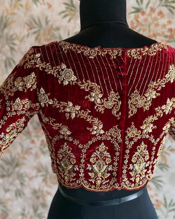 The back of a bridal maroon velvet blouse. The heavy zardozi work creates a pattern that is both intricate and symmetrical, fit for a queen.