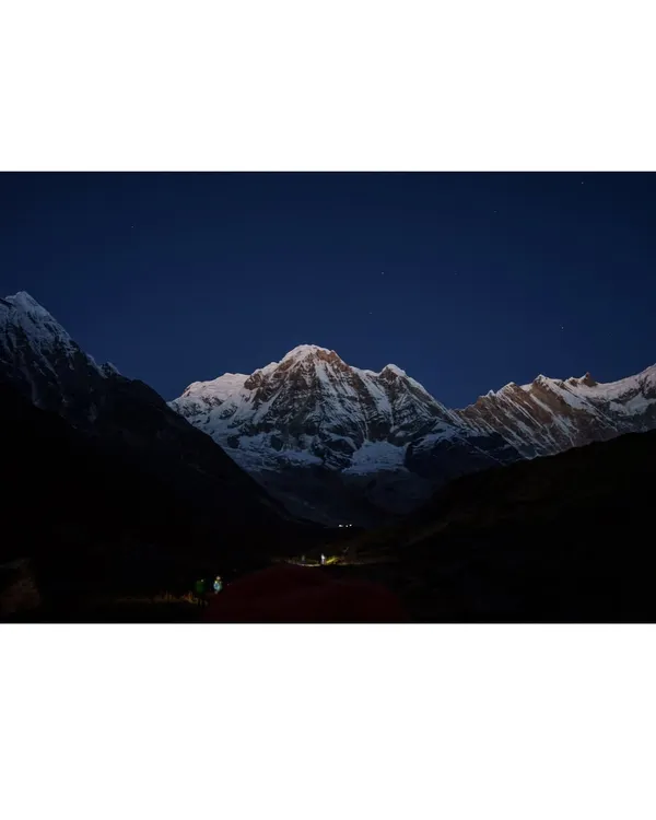 The majestic, snow-covered peak of Annapurna glowing under the night sky. We organize high-altitude Himalayan treks for those seeking the ultimate adventure.