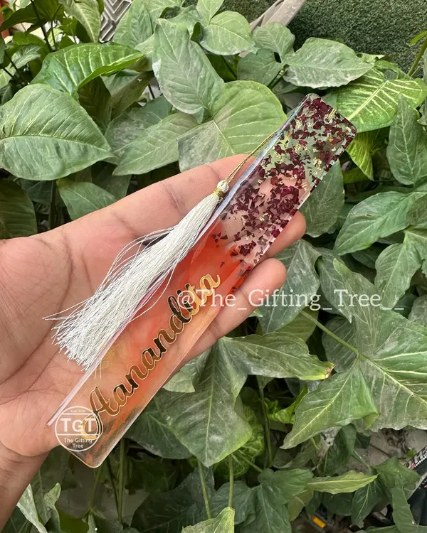 A personalized resin bookmark with the name "Anandita" in gold. The design features a mix of colors, shimmer, and a white tassel.