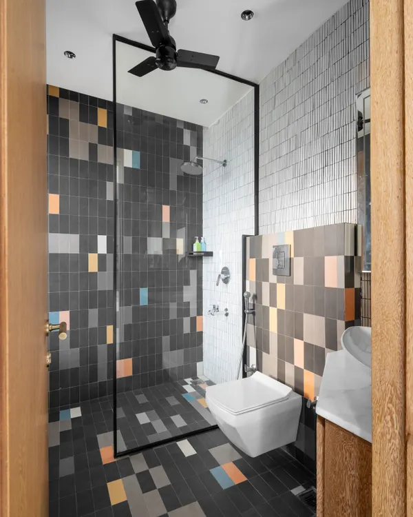 This kid's washroom features playful, pixel-style tiles in multiple colors, creating a fun and energetic vibe. We used continuous tiling on the floor and shower wall to make the compact space feel larger and more immersive.